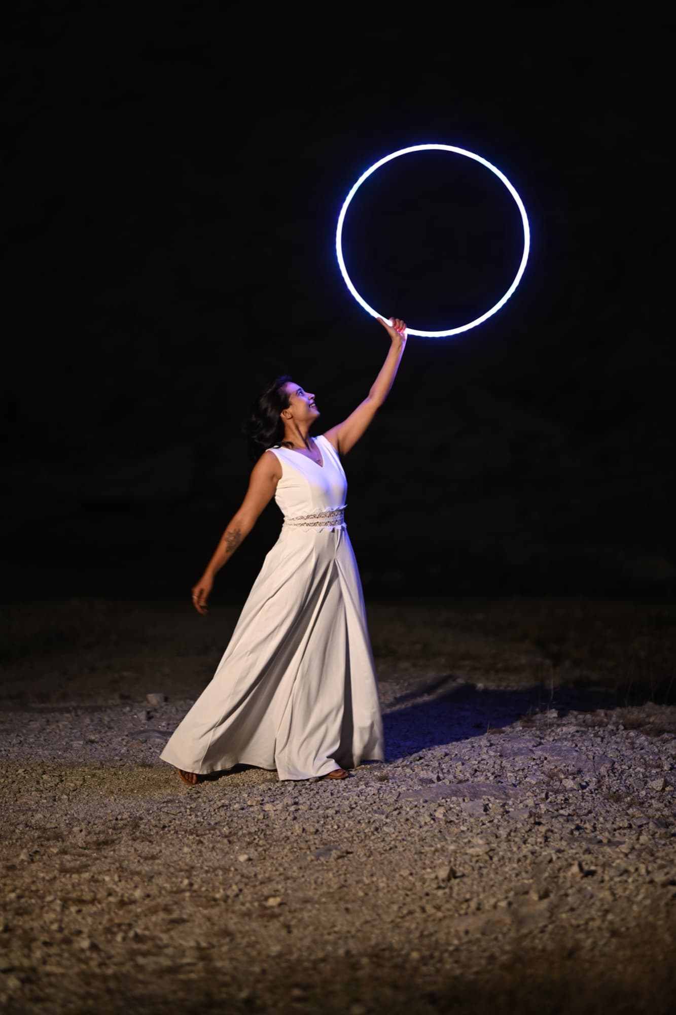 Devina holding a glowing LED hoop overhead at night