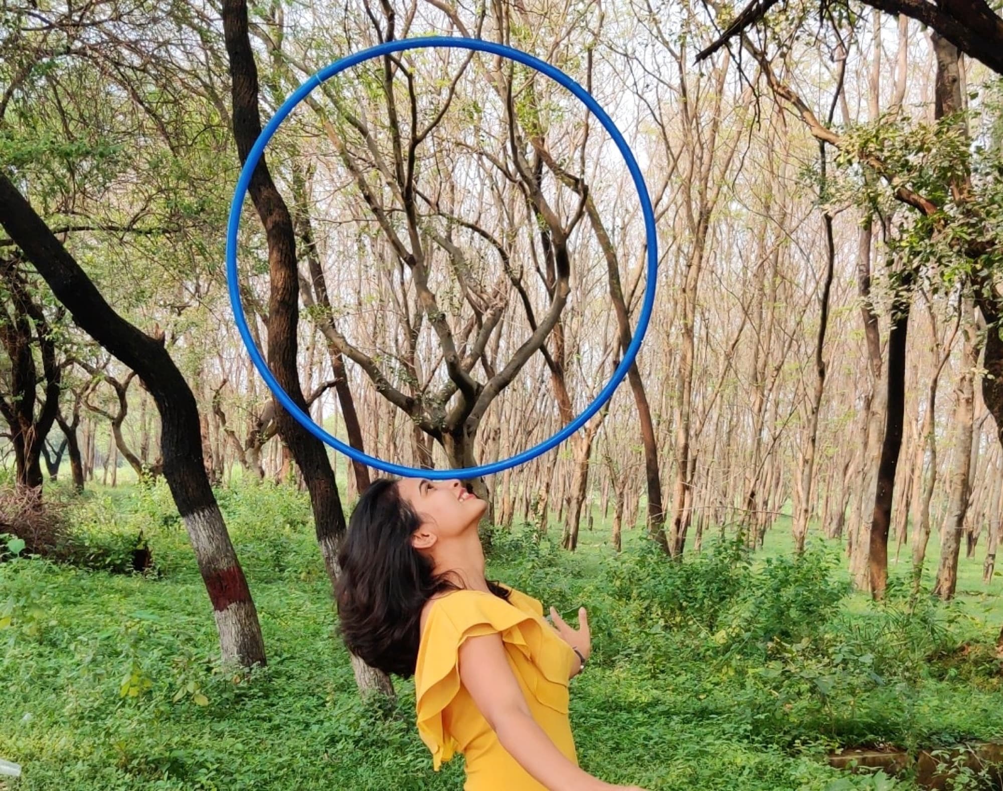 Devina looking up at a hula hoop in a forest
