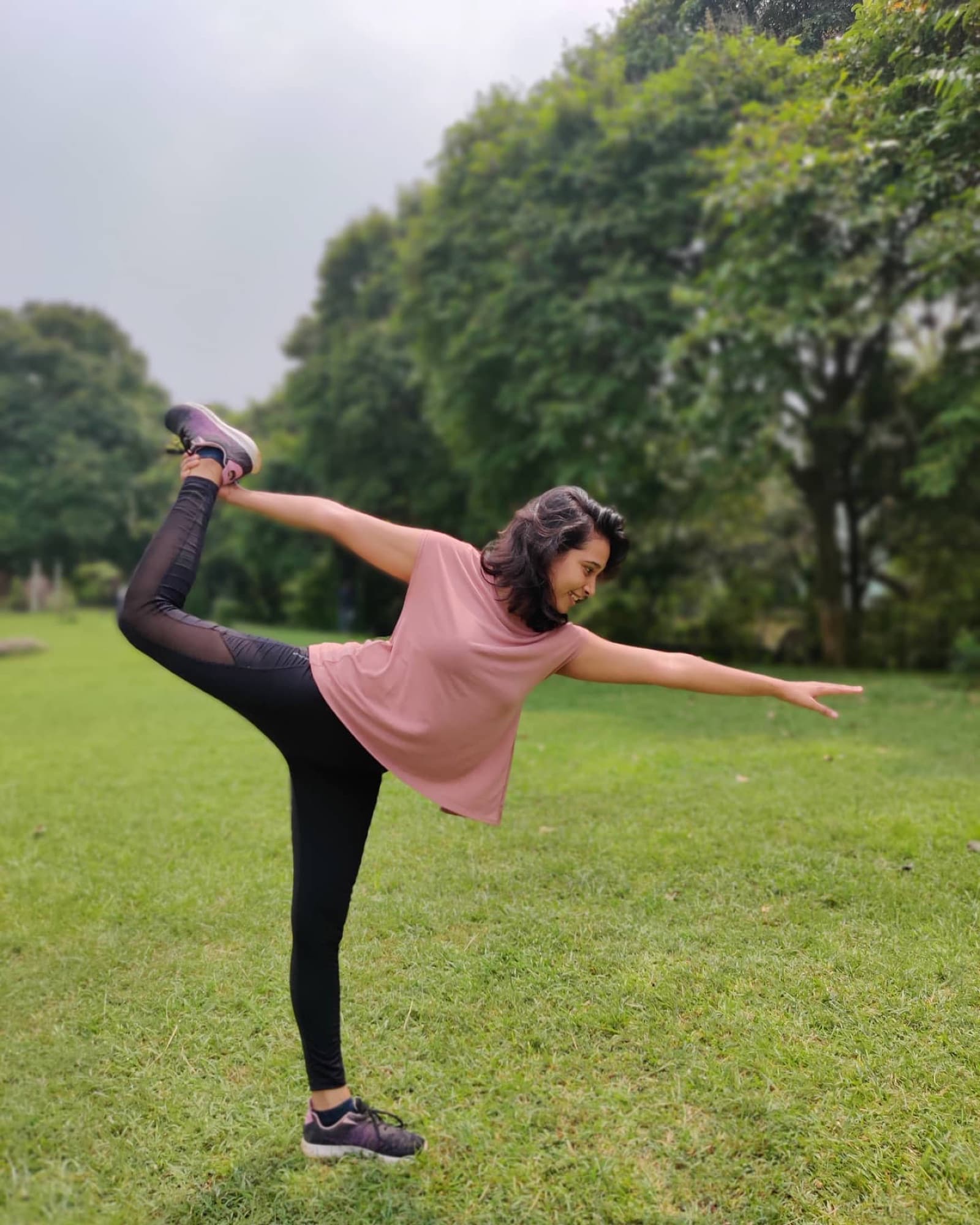 Devina in a standing yoga pose in a park